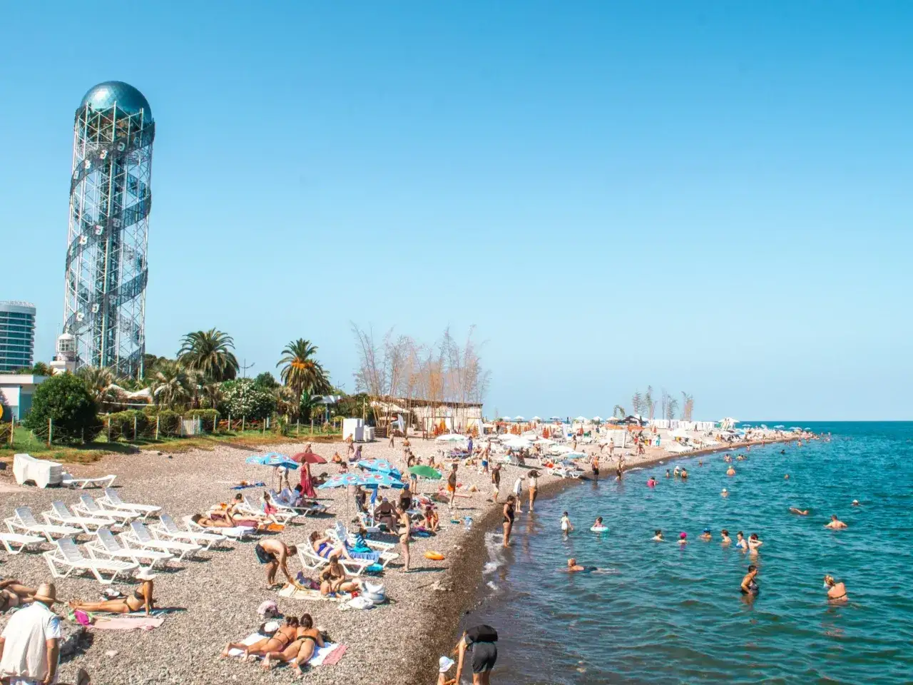 Tłum ludzi na plaży w Batumi, Gruzja. W tle charakterystyczna wieża. Odpowiedź na pytanie: czy w Gruzji jest bezpiecznie? Tak, plaże są pełne turystów.