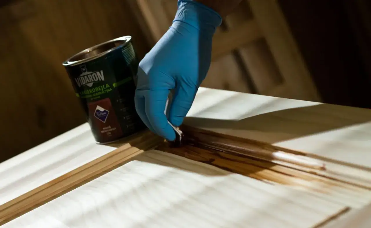 Rękawiczka z gąbką nakłada lakierobejcę Vidaron na drewno. Idealne rozwiązanie, czym pomalować taras drewniany.