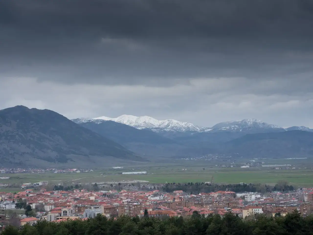 Widok na miasto Korce w Albanii z ośnieżonymi górami w tle.