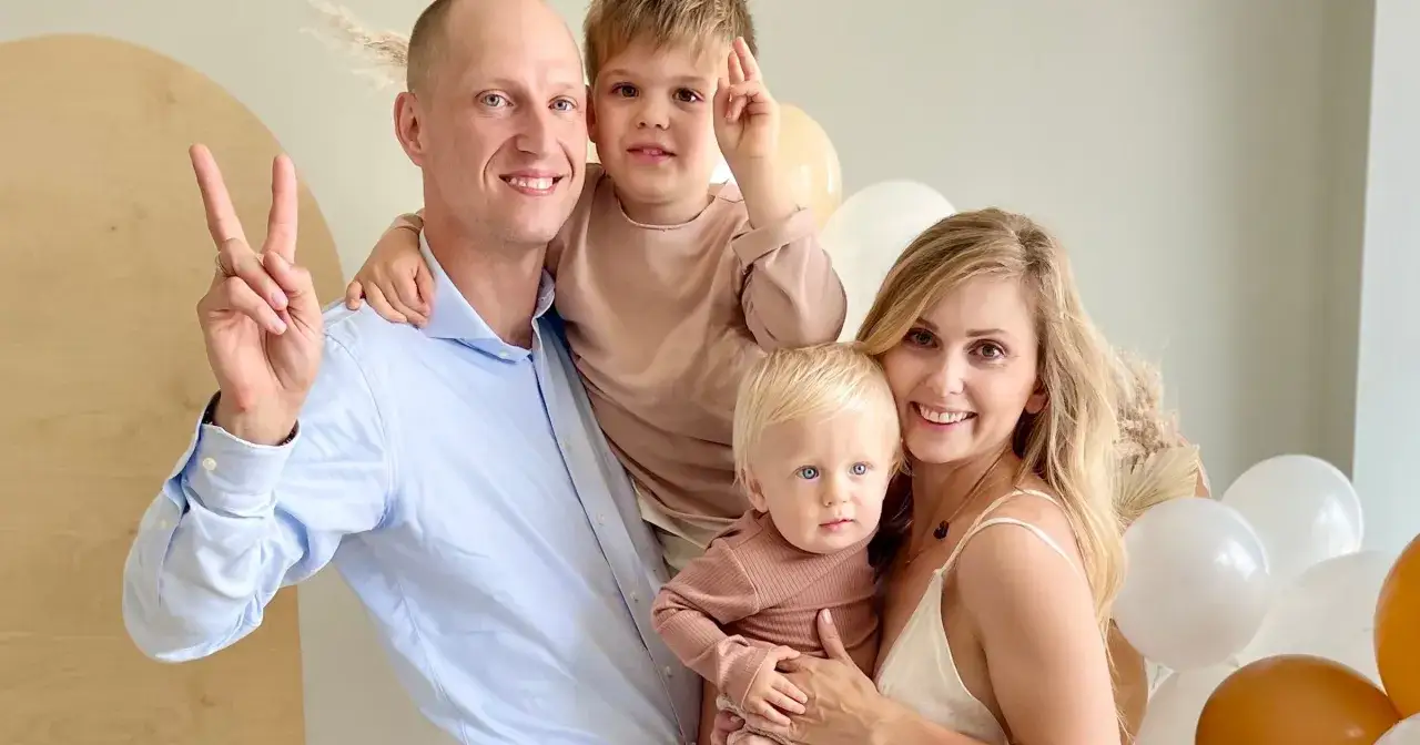 Katarzyna z mężem i dziećmi, uśmiechnięci, w otoczeniu balonów.