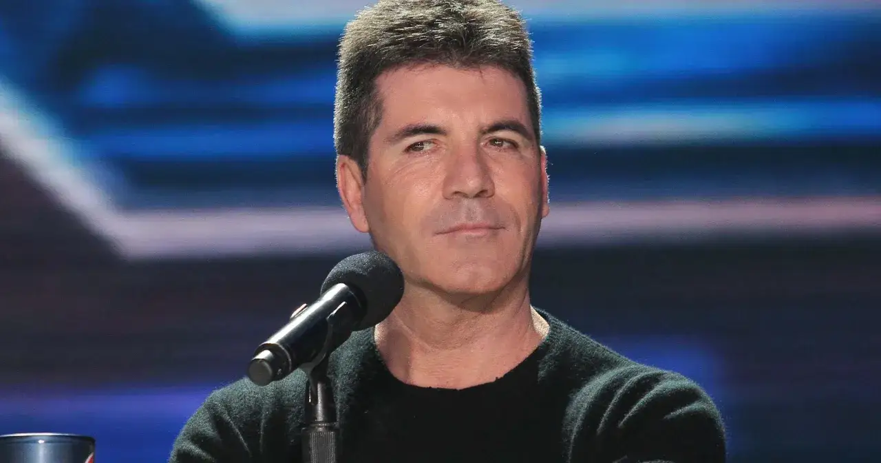 Simon Cowell przed mikrofonem, wygląda na zamyślonego. Plotki o tym, czy Simon Cowell nie żyje, są nieprawdziwe.