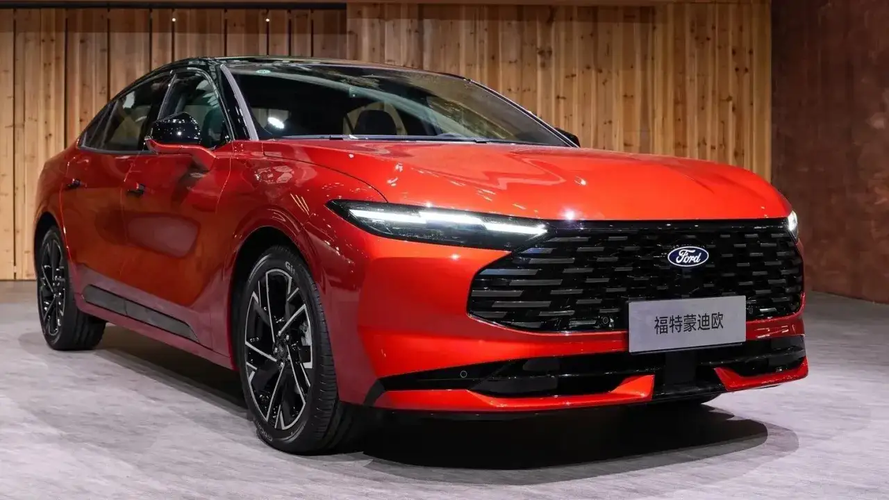 Nowy, lśniący, czerwony Ford Mondeo MK5 z czarnym dachem i felgami prezentuje się elegancko na tle drewnianej ściany.