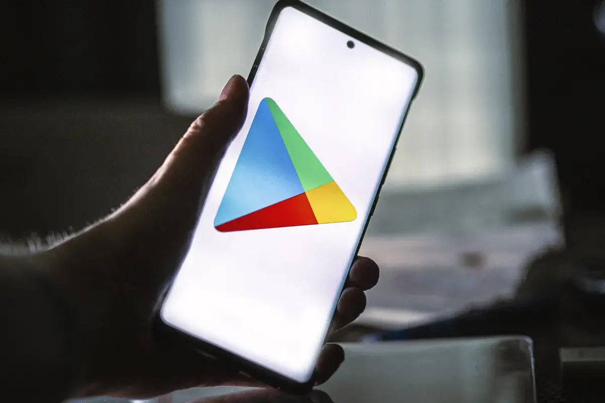 Dłoń trzyma smartfon z widocznym logo Sklepu Google Play.
