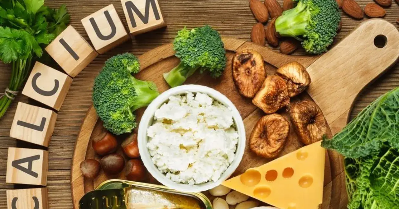 Drewniane klocki z napisem "CALCIUM", brokuły, ser, figi, migdały, orzechy i sardynki.