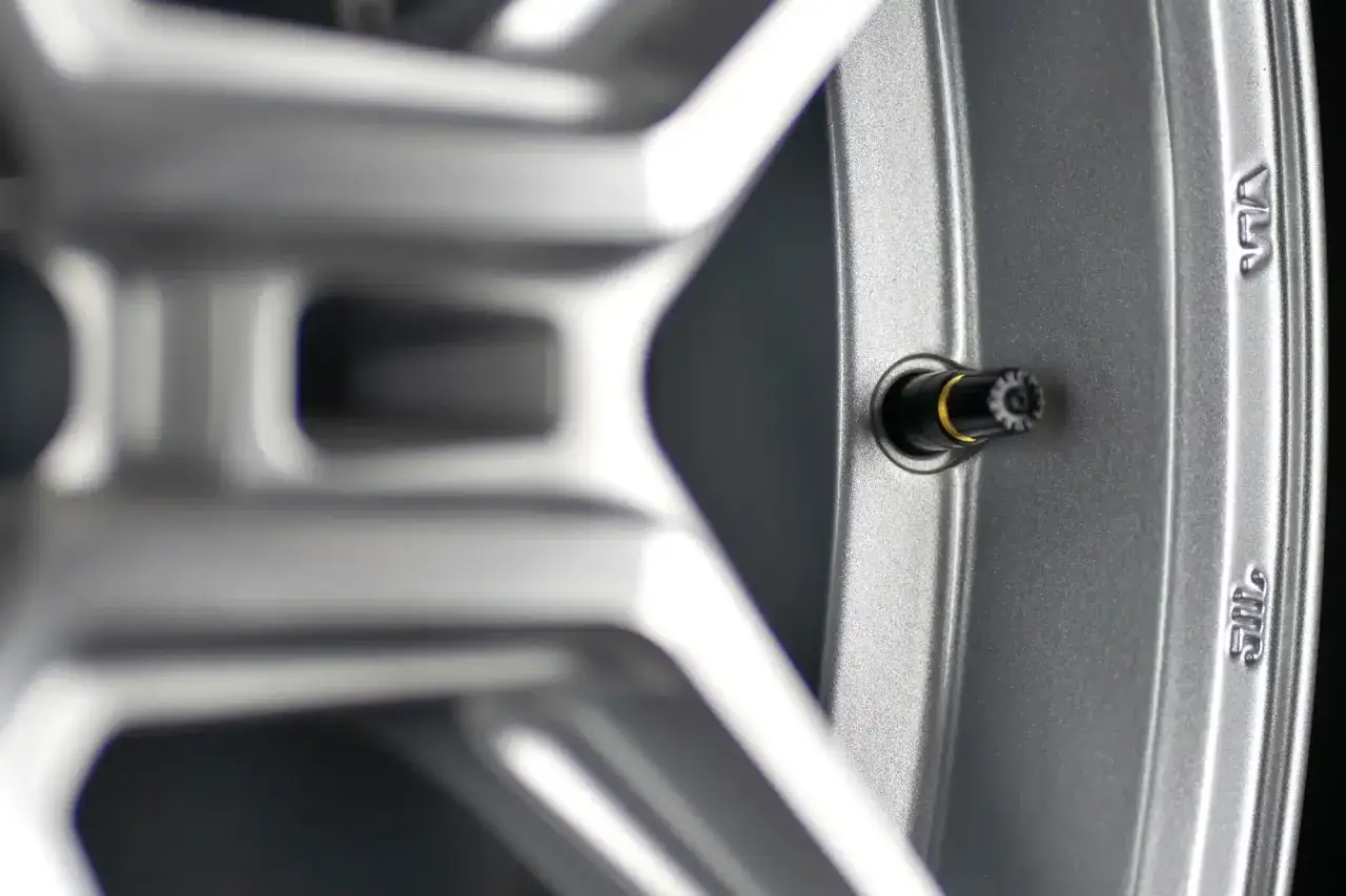 Szukasz informacji, jak dobrać wentyl do felgi? Zobacz zbliżenie na wentyl w srebrnej feldze aluminiowej.