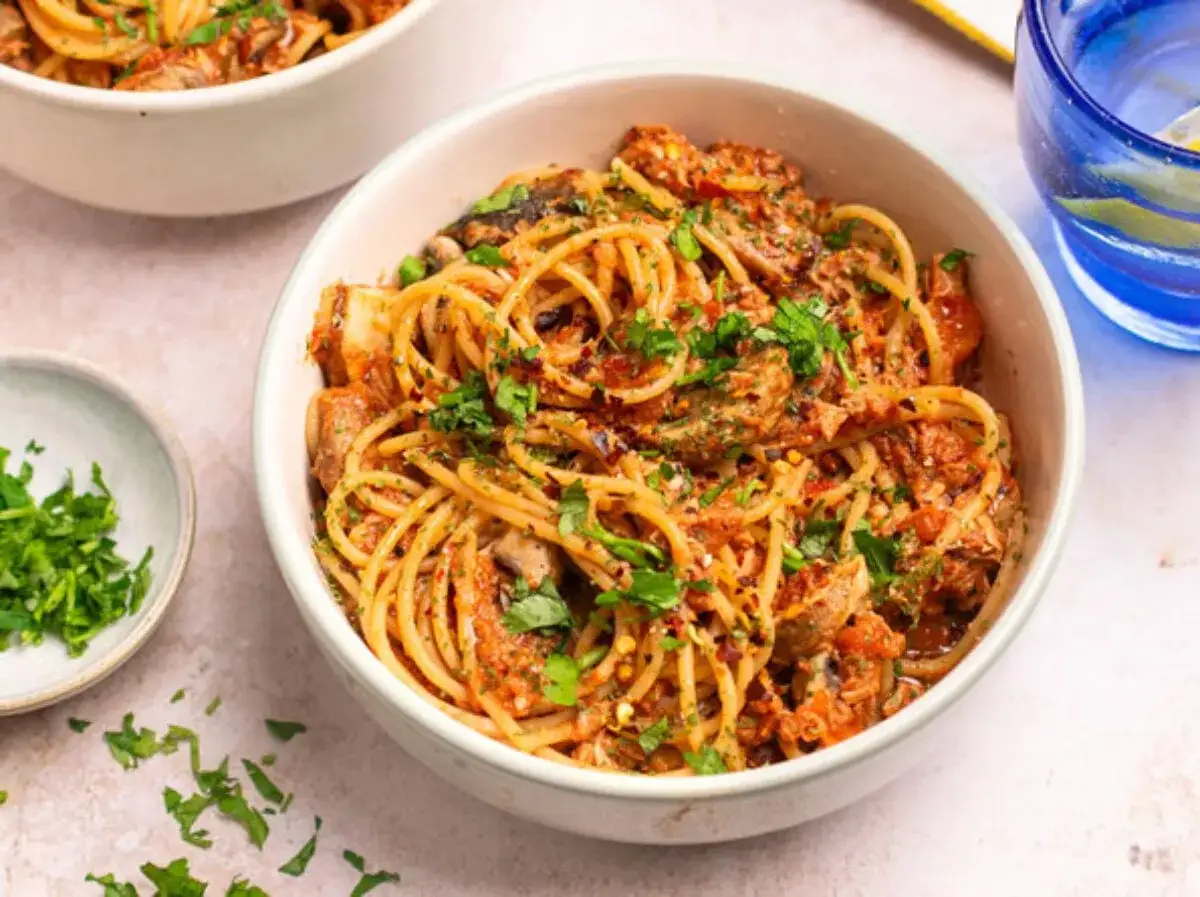 Miseczka spaghetti z sosem pomidorowym, grzybami i posiekaną natką pietruszki.