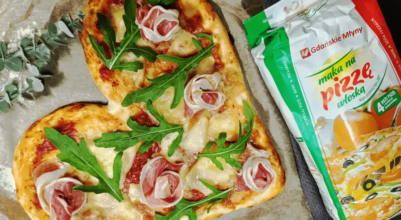 Serce z pizzy z rukolą i szynką, obok mąka do pizzy. Idealne do pieczenia pizzy w piekarniku.
