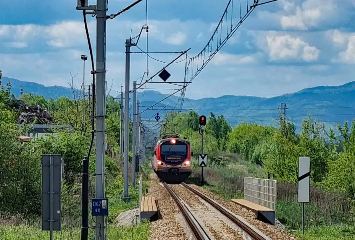 Pociąg zbliża się do stacji, a krajobraz zapowiada podróż, jak dojechać pociągiem do Krynicy-Zdroju.
