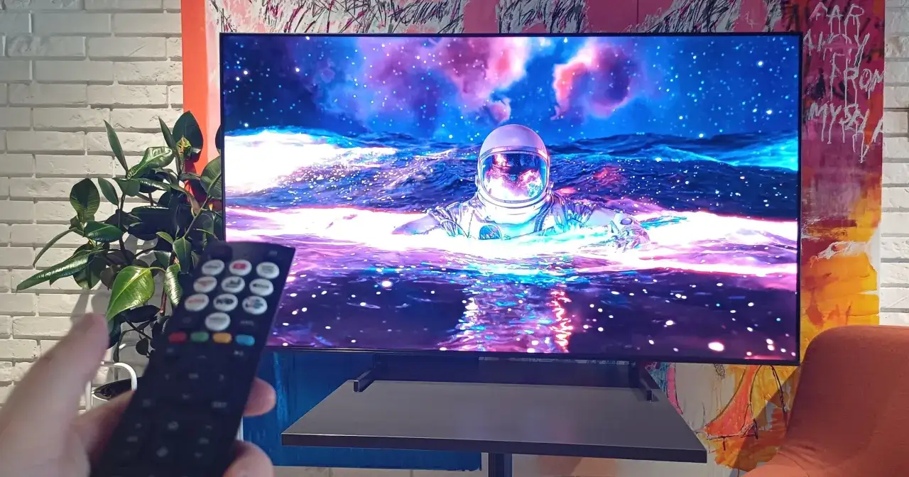 Telewizor wyświetla astronautę w kosmosie, trzymany jest pilot.