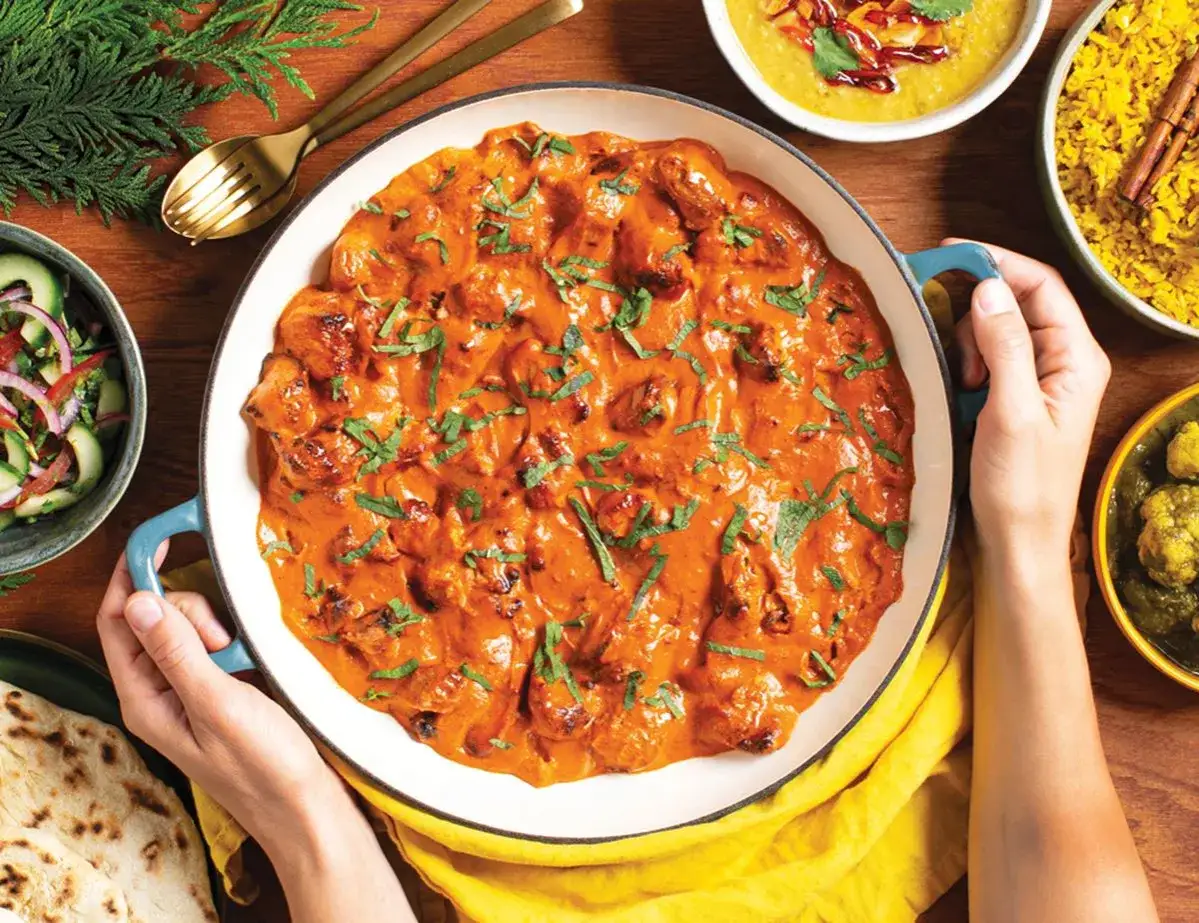 Pyszny butter chicken przepis w kremowym sosie, podany z ryżem, sałatką i chlebkiem naan.