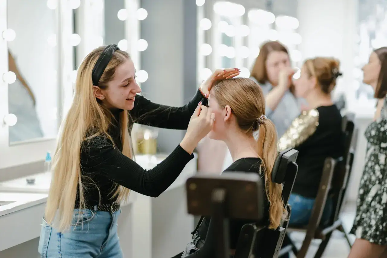 Uczestniczki szkoleń beauty ćwiczą makijaż przy lustrach z oświetleniem.