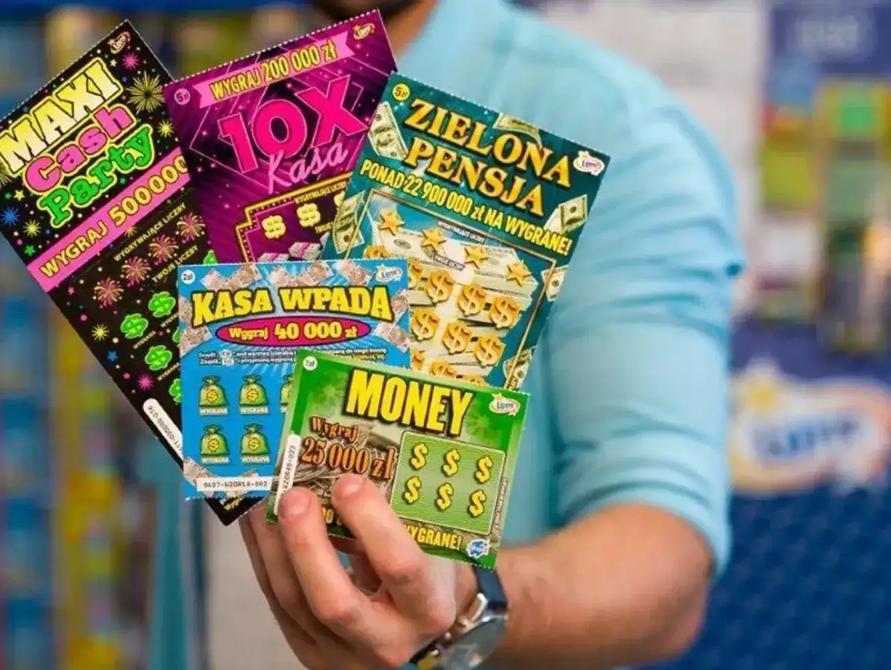 Ręka trzyma kilka zdrapek, sugerując pytanie: czy warto grać w zdrapki? Widać nazwy jak "Maxi Cash Party", "10x Kasa", "Zielona Pensja", "Kasa Wpada", "Money".