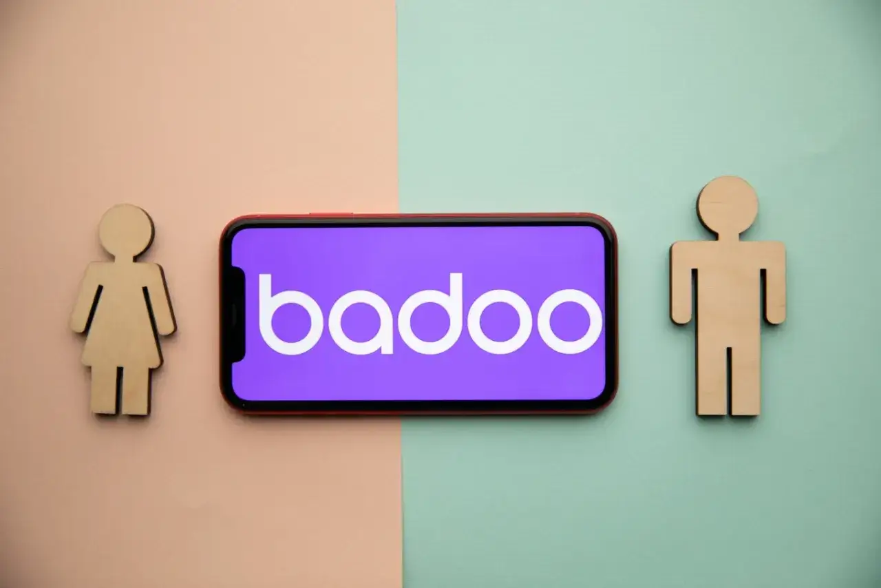Drewniane figurki kobiety i mężczyzny po bokach telefonu z logo Badoo. Czy to portal randkowy?