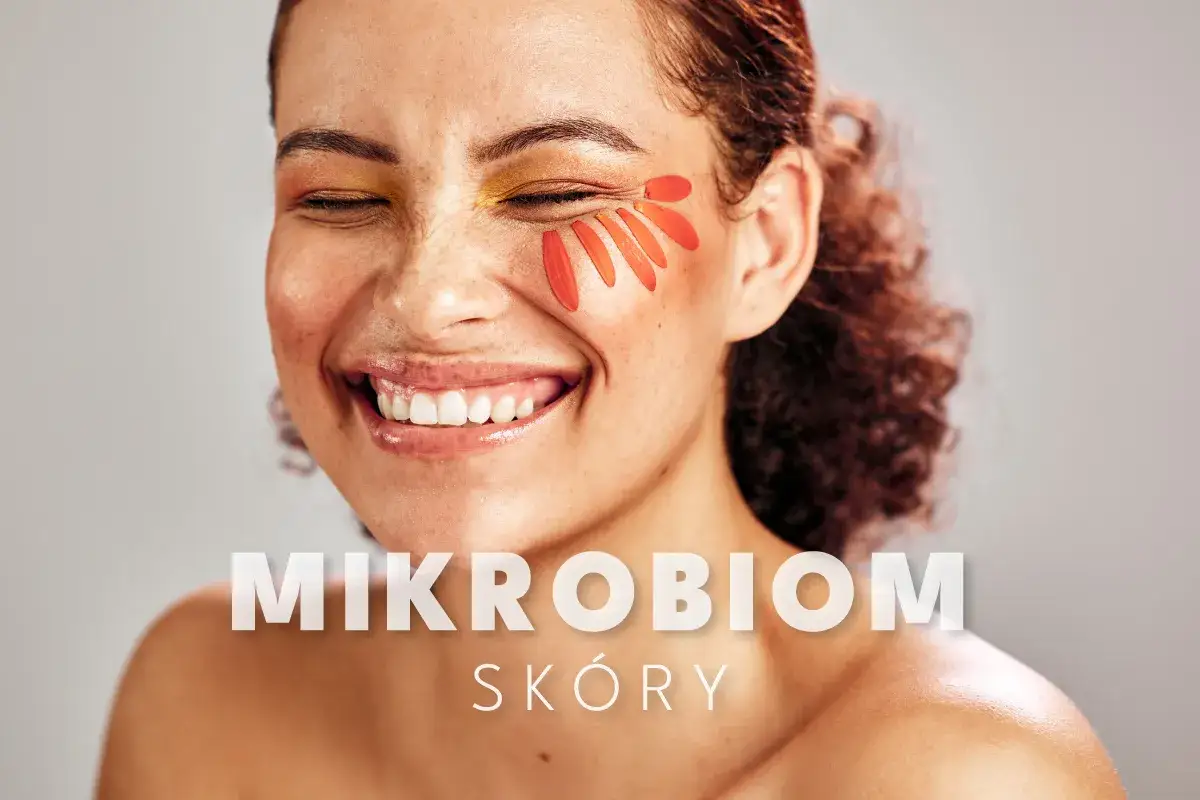 Uśmiechnięta kobieta z płatkami kwiatów na policzku. Tekst: "MIKROBIOM SKÓRY".