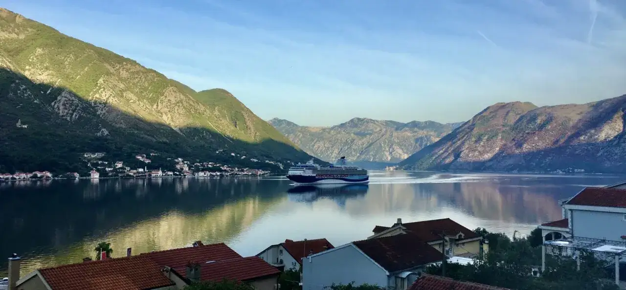 Widok na Zatokę Kotorską, gdzie statek wycieczkowy płynie w kierunku wybrzeża. Czy Czarnogóra jest bezpieczna? Tak, to spokojne miejsce.