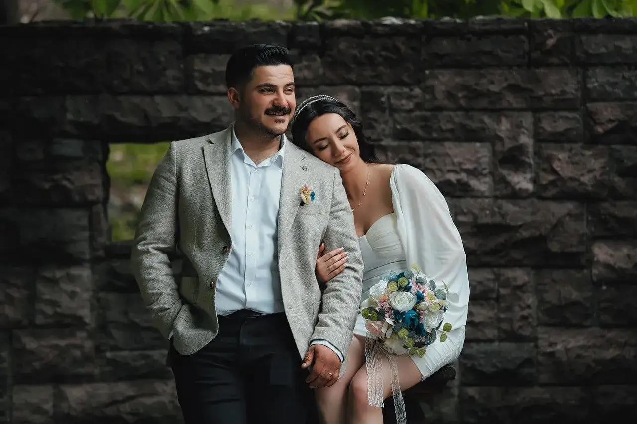 Para młoda w stylizacjach ślubnych na tle kamiennej ściany.