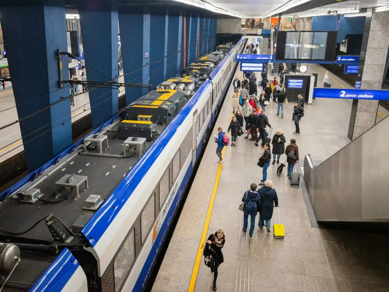 Ludzie z bagażami na peronie czekają na pociąg Intercity. Można zabrać walizki, plecaki i torby.
