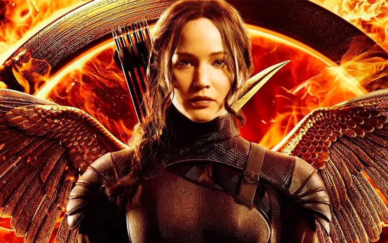 Katniss Everdeen z łukiem i strzałami, w zbroi z piórami, na tle płomieni. Gdzie obejrzeć Igrzyska Śmierci?