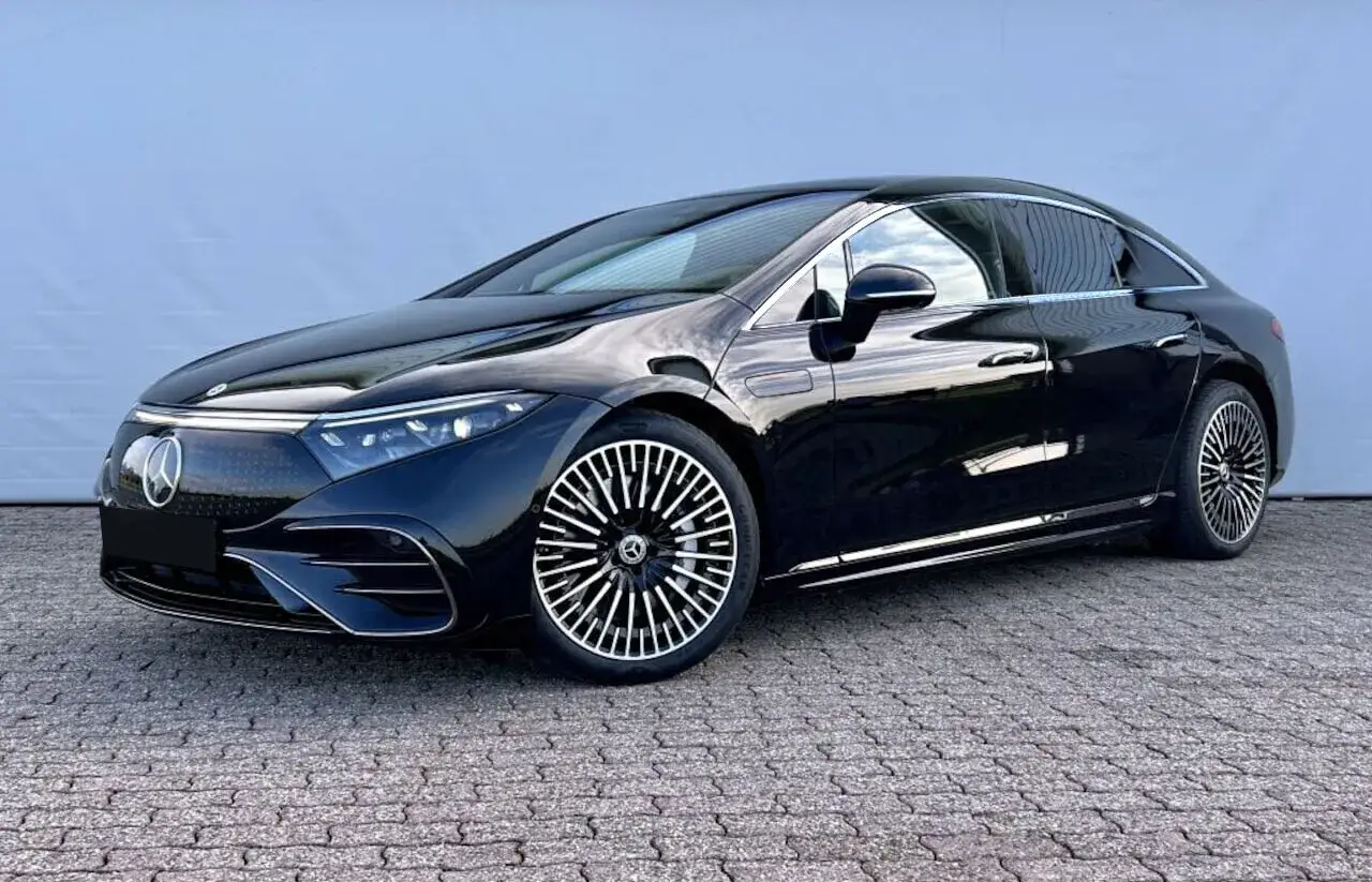 Czarny Mercedes-Benz EQS, jeden z samochodów elektrycznych o największym zasięgu, lśni na tle błękitnej ściany.