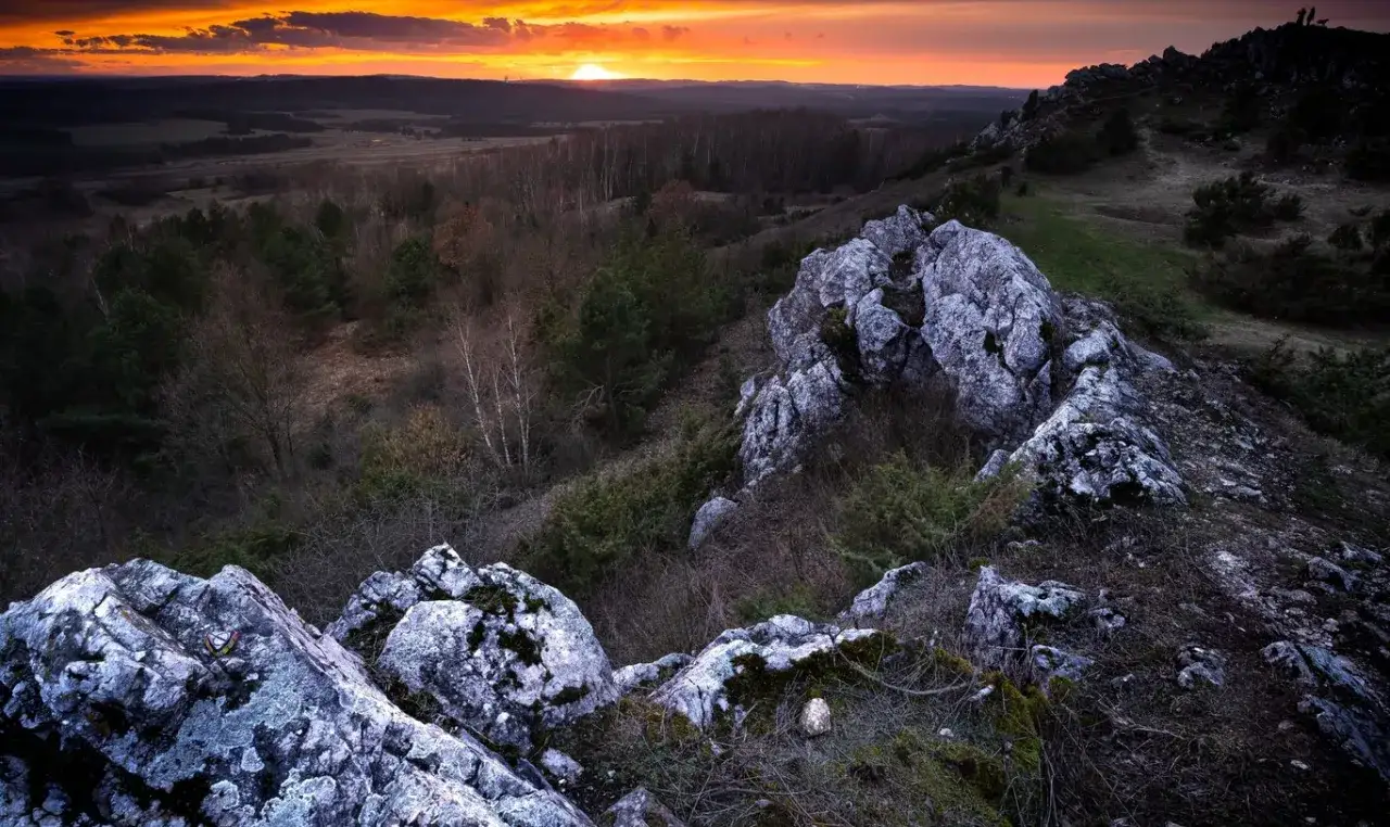Zachód słońca nad Górami Świętokrzyskimi. Skaliste szczyty i lasy tworzą malowniczy krajobraz. Idealne miejsce, by zobaczyć piękno polskiej przyrody.