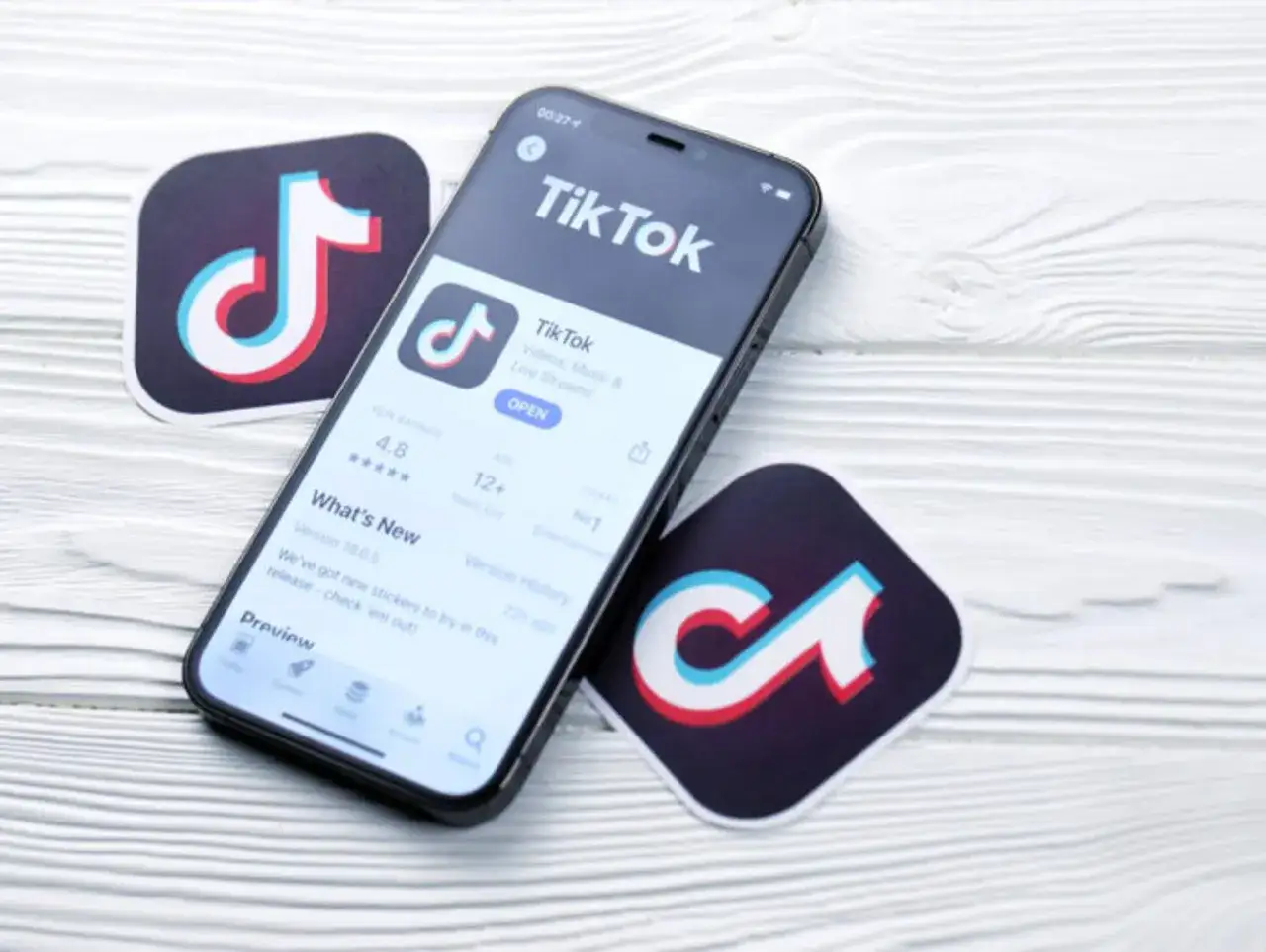 Telefon z aplikacją TikTok i logotypy platformy. Zastanawiasz się, ile zarabia się na tiktoku za 1000 wyświetleń?
