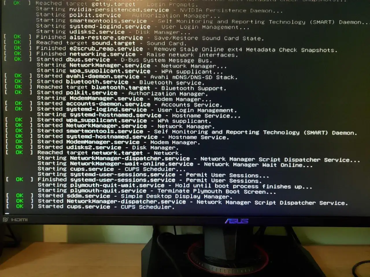 Ekran z logami startowymi systemu Linux, widoczne są komunikaty o uruchamianiu usług, w tym NetworkManager i dkms.