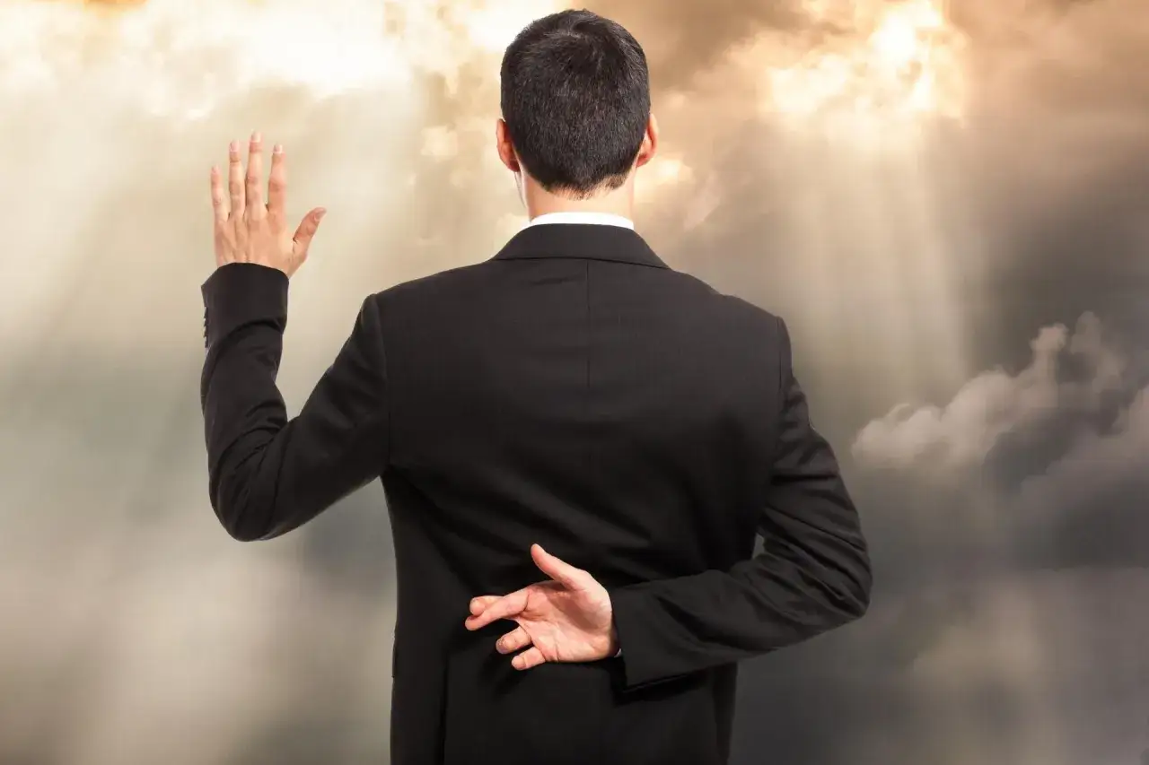 Mężczyzna w garniturze podnosi rękę do przysięgi, drugą rękę z założonymi palcami trzyma za plecami. Oto jak postępować z hipokrytą.