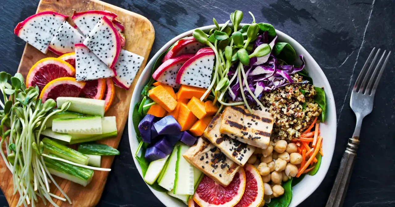 Kolorowa miska pełna zdrowia: grillowane tofu, komosa ryżowa, warzywa i owoce. To właśnie wegańskie co to znaczy – pyszne i odżywcze!