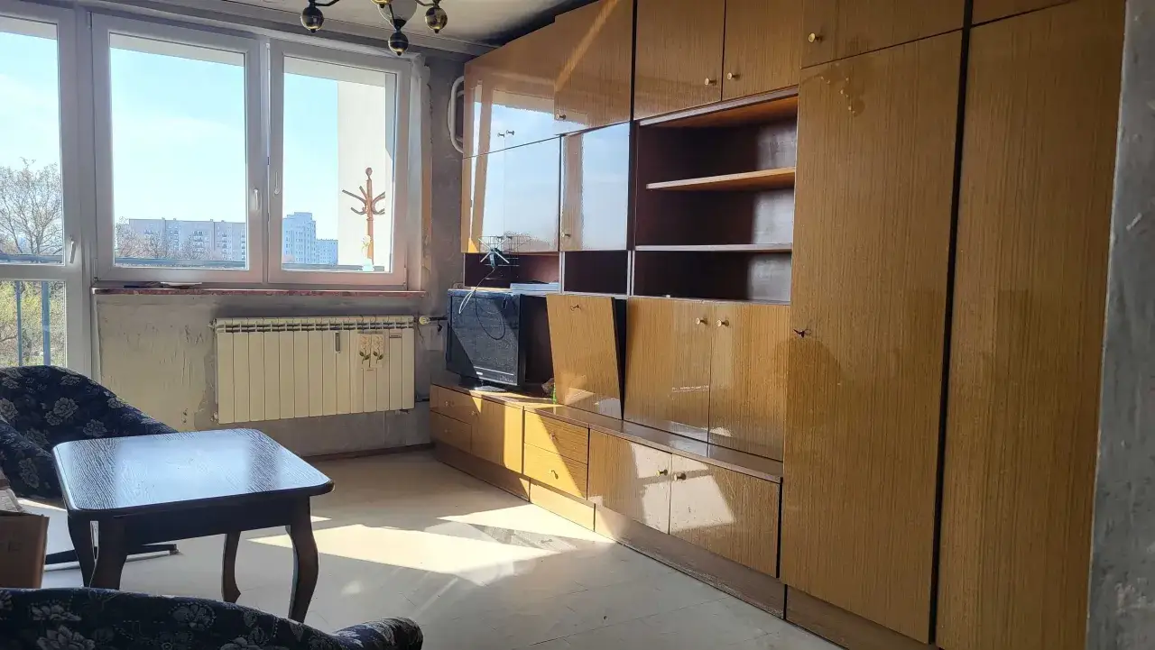 Tanie mieszkania na sprzedaż Sosnowiec bez pośredników. Widok na pokój z meblościanką, fotelem i stolikiem.