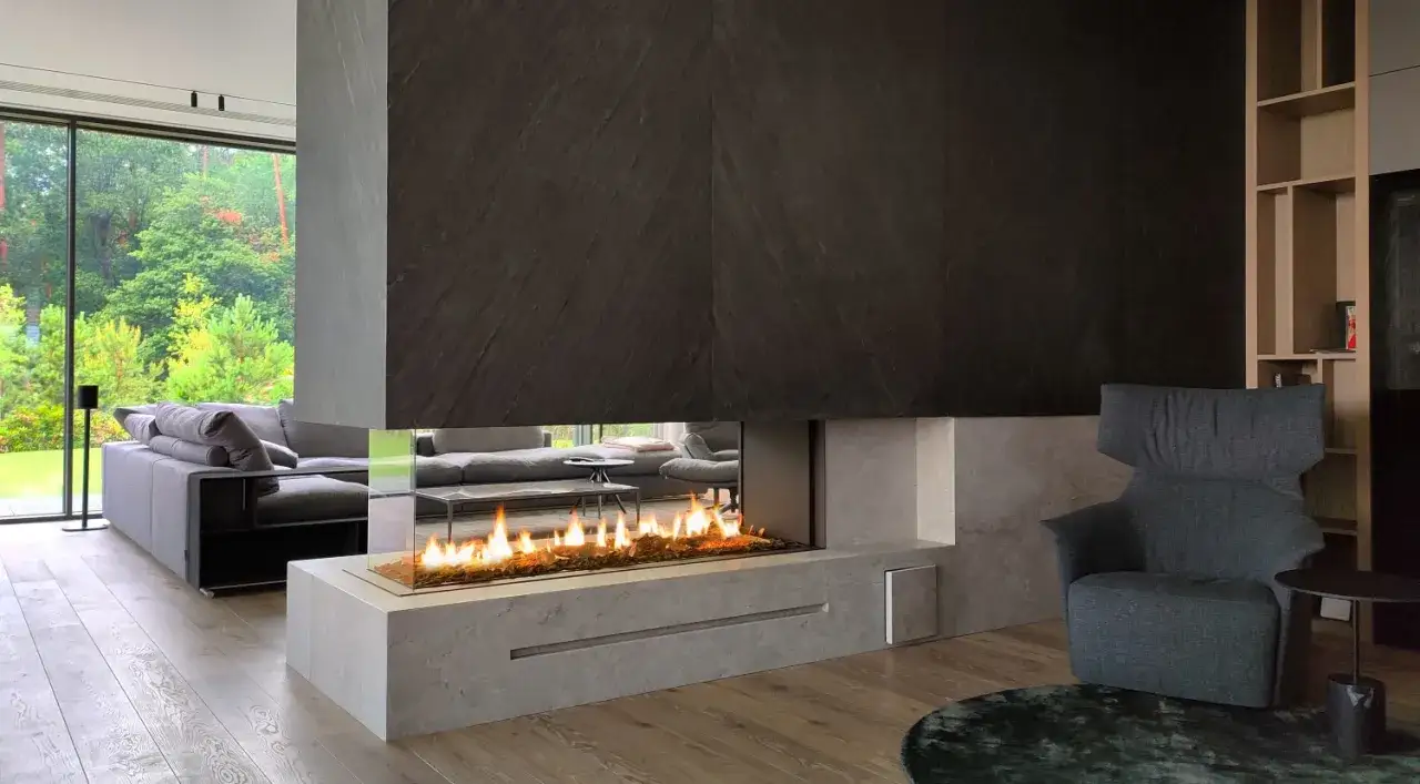 Nowoczesny salon z panoramicznym oknem i wkładem elektrycznym do kominka, tworzącym przytulną atmosferę.