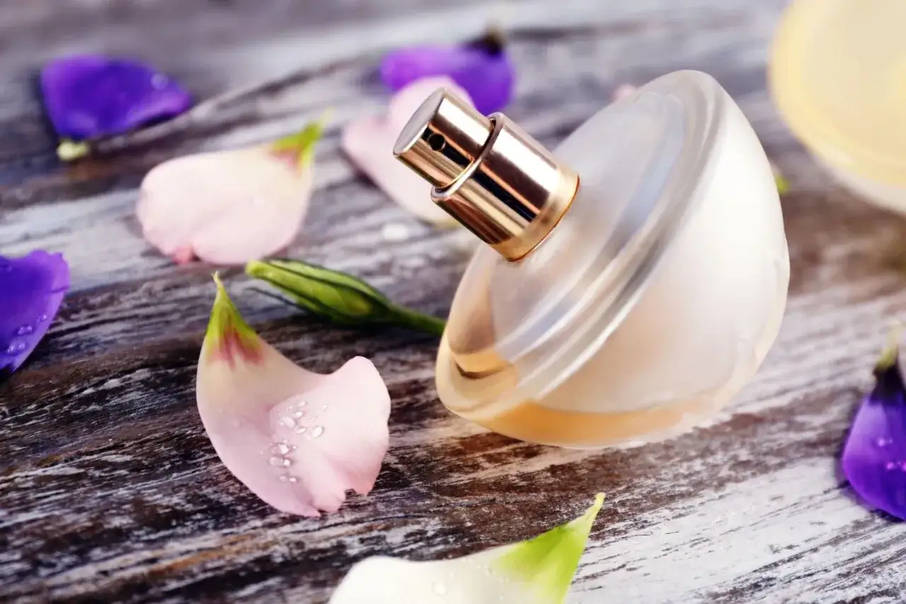 Perfumy w szklanej butelce, otoczone płatkami kwiatów. To idealny moment na refill, czyli uzupełnienie ulubionego zapachu.