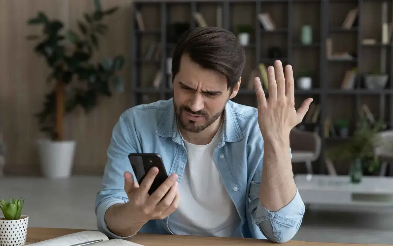 Mężczyzna zmartwiony przegrzewaniem się telefonu. Dba o bezpieczną temperaturę urządzenia, by uniknąć uszkodzeń.