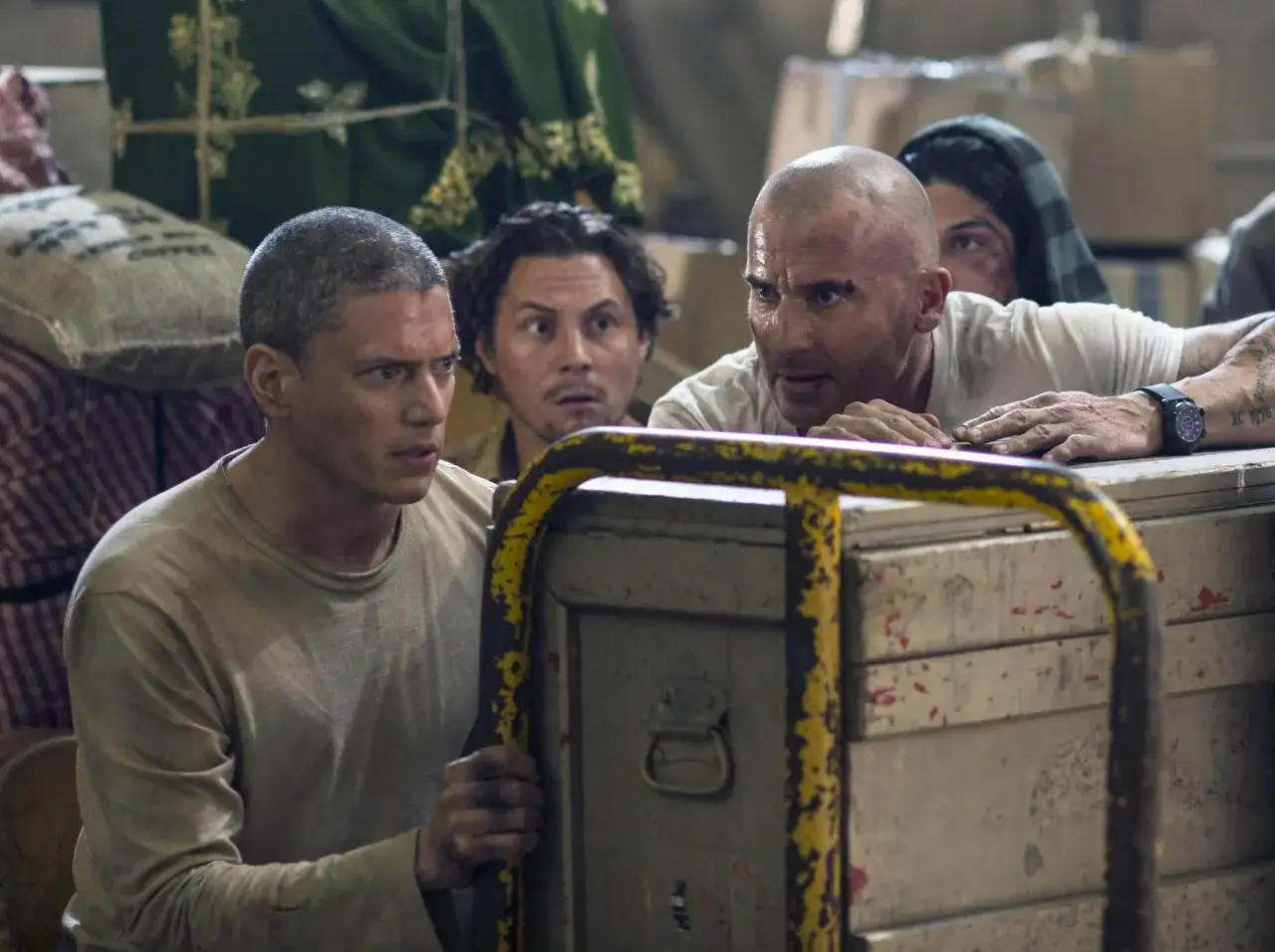 Dwóch mężczyzn, jeden skazany na śmierć, spogląda z napięciem na coś za skrzynią.