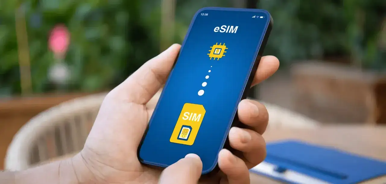 Dłoń trzyma smartfon z ekranem pokazującym ikonę karty SIM i symbol chipa, symbolizujące kartę eSIM.