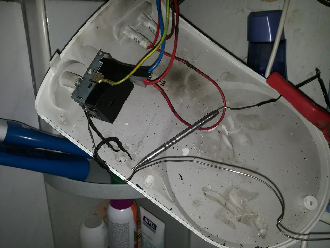 Rozmontowany bojler z widocznym termostatem i przewodami. Jak sprawdzić termostat w bojlerze? To zdjęcie pokazuje wnętrze, gdzie znajduje się element grzewczy i okablowanie.