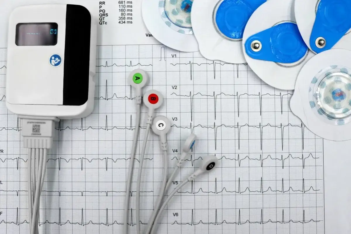 Elektrokardiograf i elektrody do badań serca na tle zapisu EKG.