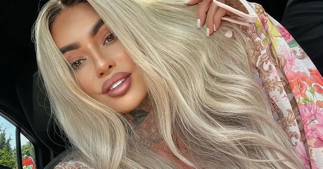 Ania Królowe Życia z blond włosami i tatuażem na szyi, w kwiecistej bluzce.