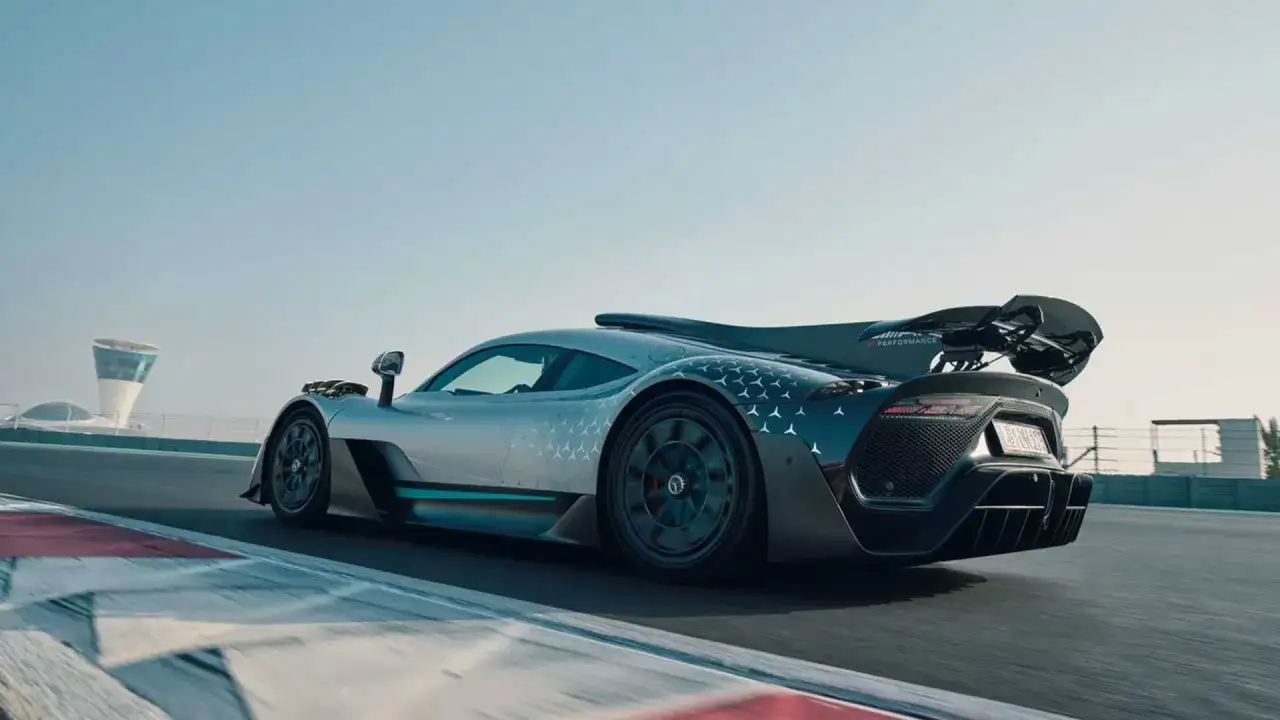 Srebrny Mercedes-AMG ONE z charakterystycznym wzorem gwiazdek na karoserii pędzi po torze wyścigowym.