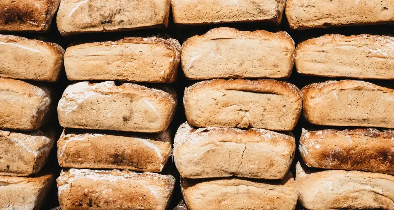Stos chleba, który zastanawia, czy pies może jeść chleb. Każdy bochenek ma złocistą skórkę i lekko posypany mąką.