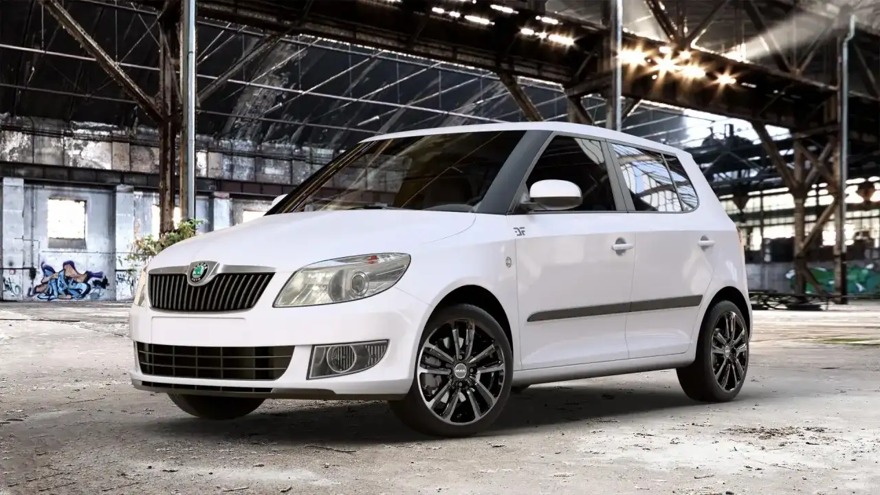 Biała Skoda Fabia z czarnymi felgami stoi w opuszczonej hali. Rozmiar opon idealnie pasuje do sportowego charakteru auta.