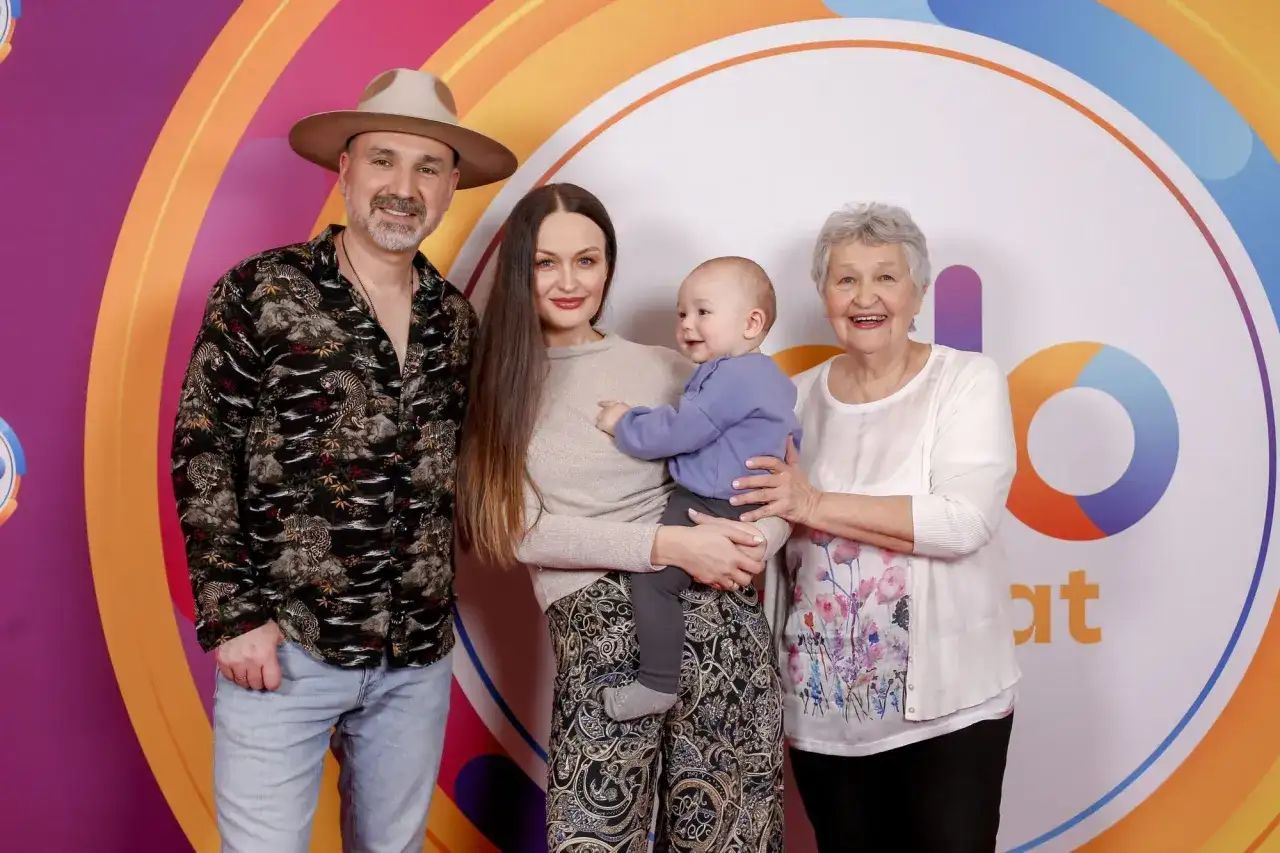Mateusz Ziółko z rodziną: żoną, synkiem i mamą na tle kolorowego logo.