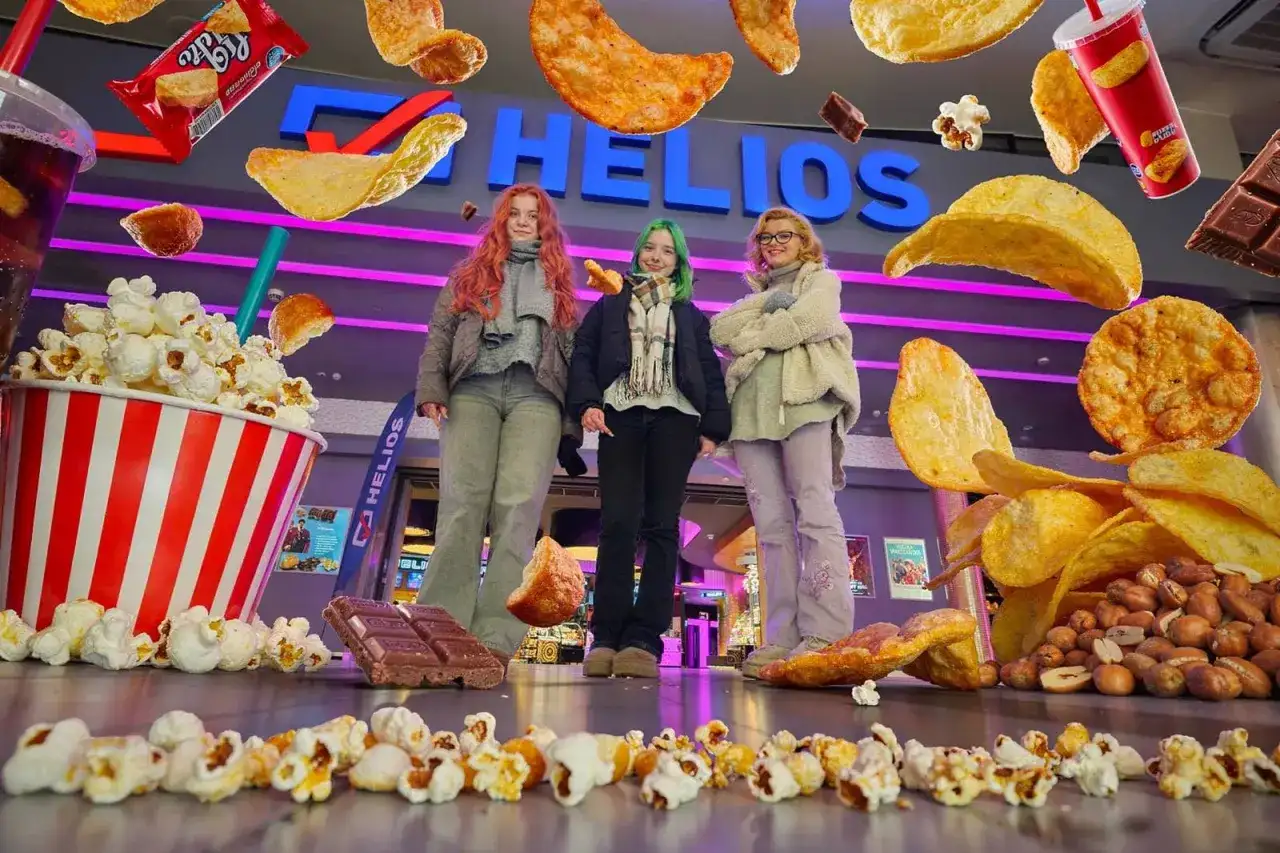 Trzy dziewczyny przed kinem Helios, otoczone przez gigantyczne przekąski. Zastanawiasz się, ile kosztuje mały popcorn w Heliosie?