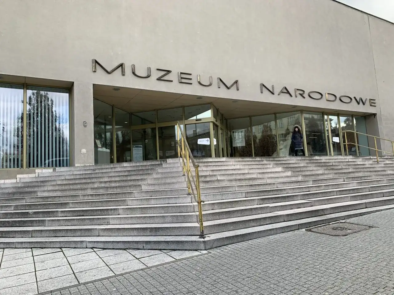 Wejście do Muzeum Narodowego w Poznaniu z szerokimi kamiennymi schodami i napisem na fasadzie.
