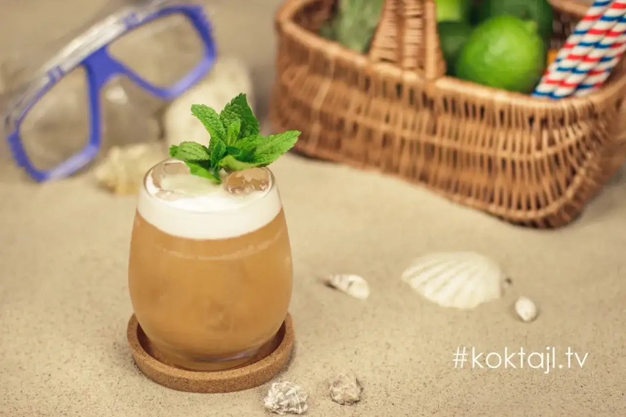 Orzeźwiający vodka sour z miętą na plaży, obok koszyka z limonkami i maski do nurkowania. Idealny na wakacje!