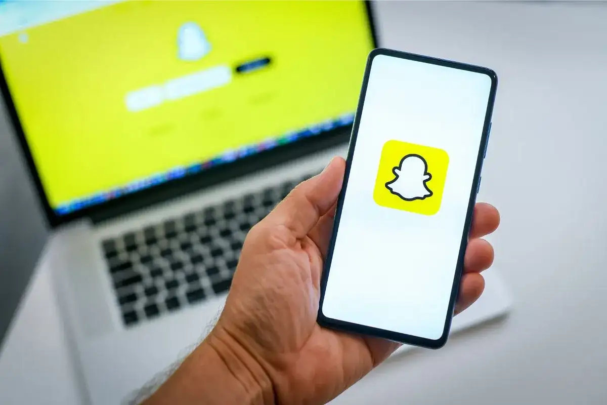 Chcesz wiedzieć, jak usunąć konto na Snapie? Na ekranie telefonu widać logo Snapchata, a na laptopie ekran logowania.