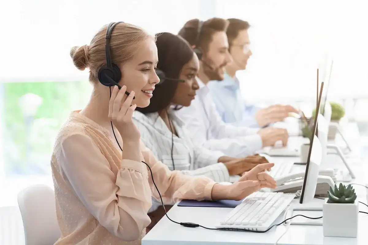 Équipe au bureau des aides régionales, en plein démarchage téléphonique. Ils sont souriants et concentrés sur leurs ordinateurs.