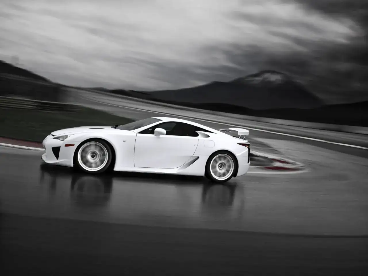 Biały Lexus LFA na torze wyścigowym, z rozmytym tłem gór i nieba.