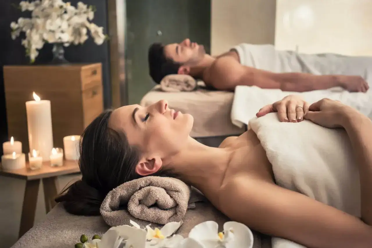 Para relaksu w spa: para leży na stołach do masażu, otoczona świecami i kwiatami. To idealne miejsce, by zapomnieć o codzienności.