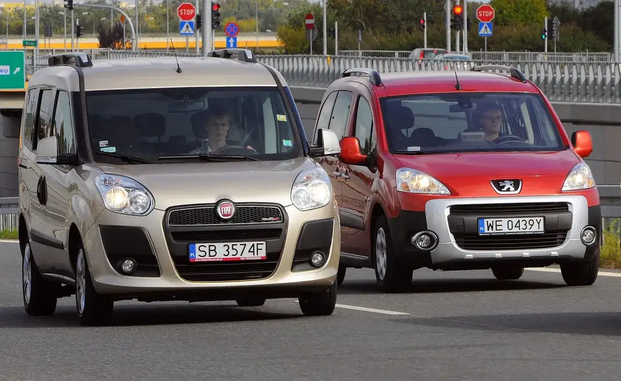 Złoty Fiat i czerwony Peugeot jadące po drodze.