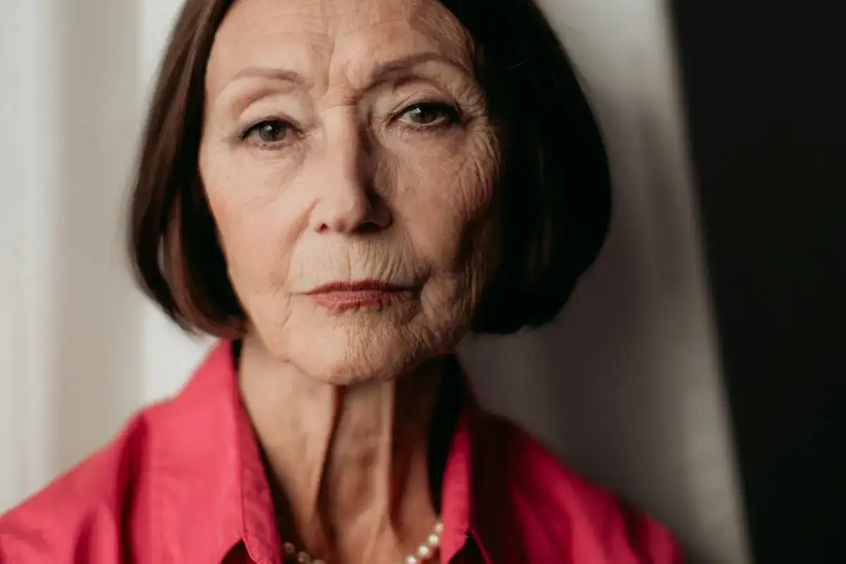 Portret starszej kobiety w różowej koszuli, z naszyjnikiem z pereł. Ewa Woydyłło-Osiatyńska, pierwsza żona, wspomina.